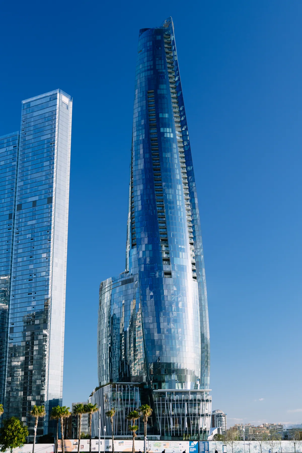 Crown Sydney's twisting glass tower against a deep blue sky at Barangaroo