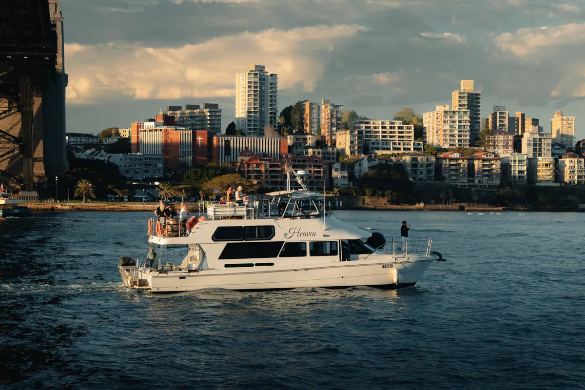 A white cruiser cutting across the harbour in front of Kirribilli apartments