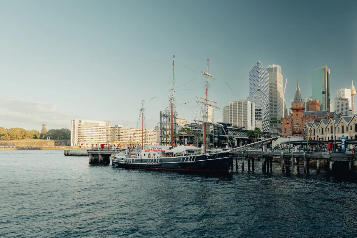 A tall ship moored at the wharves below The Rocks and the city skyline